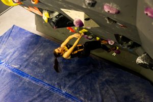 A climber works on a steep bouldering problem in our Mitchell gym.