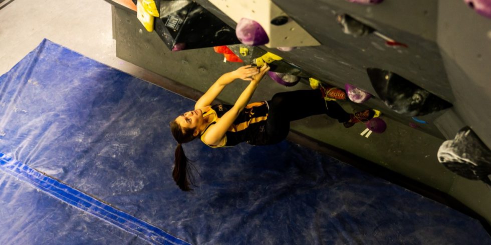 A climber works on a steep bouldering problem in our Mitchell gym.
