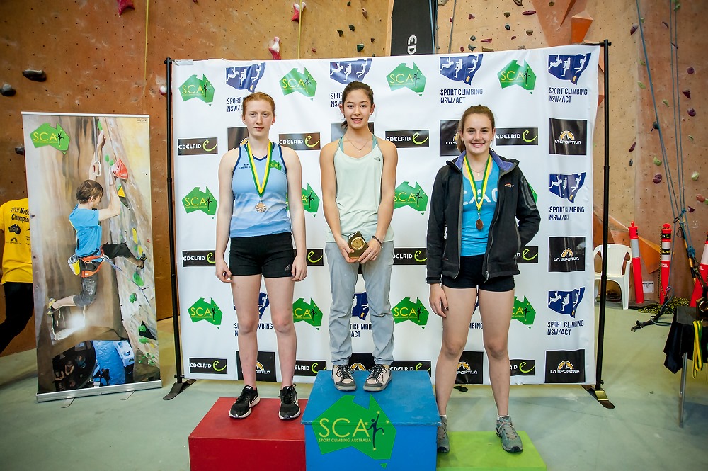 Lis Andres stands on the overall podium in her category with two other climbers.