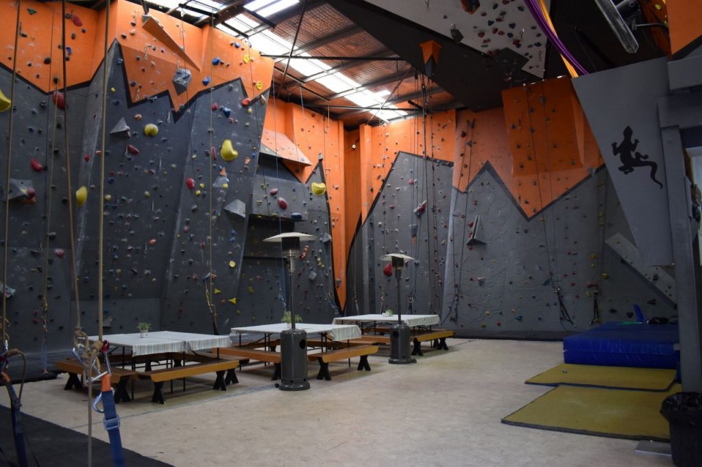 The view of our gym to the left when walking through the entrance, showing many of our climbing walls and the central table area.