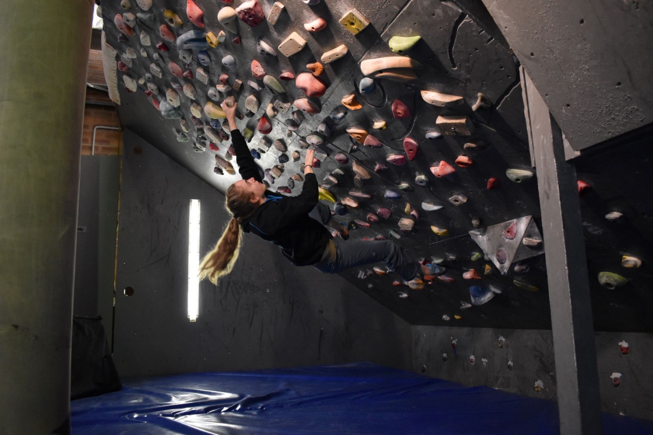 A climber ascends the steep wall in the downstairs bouldering cave.