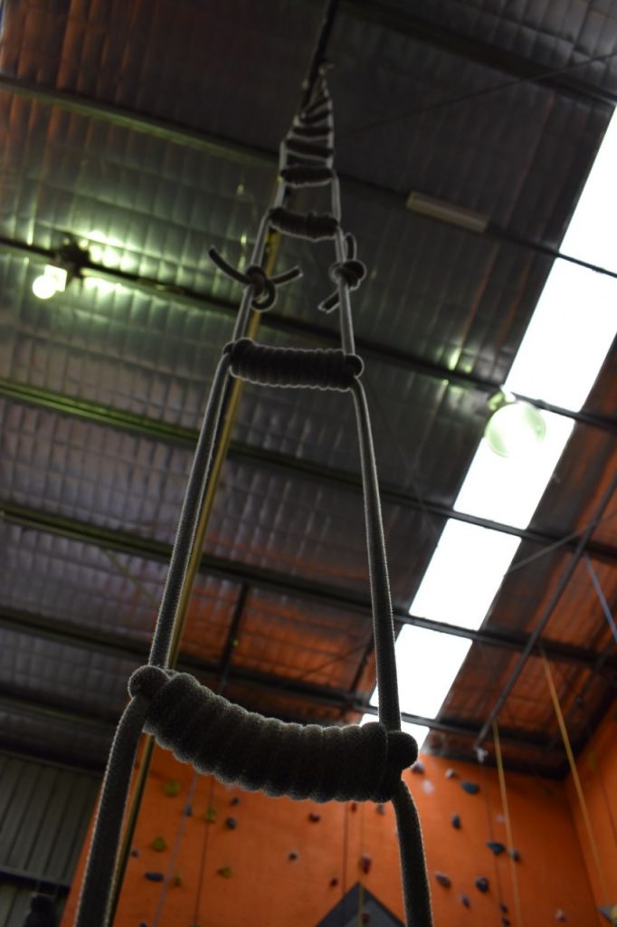 A photo taken at the bottom of a rope climbing ladder looking up to the ceiling.