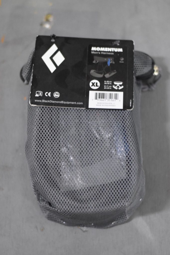 A Black Diamond XL men's Momentum harness in its grey mesh bag